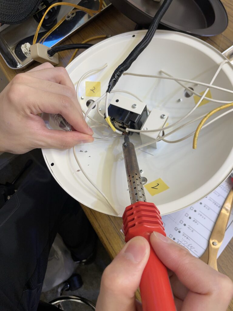 スイッチと配線構造が複雑なランプを修復している様子の画像